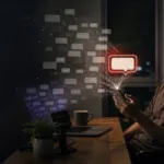 夜間工作桌前，一名男子看著手機，許多留言泡泡從手機與電腦湧出，最後收束成一個紅色回覆泡泡